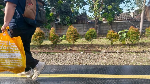 Yogyakarta Wednesday, April 22, 2026. A person walks along a train platform carrying a shopping bag, depicting daily commutes, urban lifestyles, and the use of public transportation&mdash;ideal for editoria