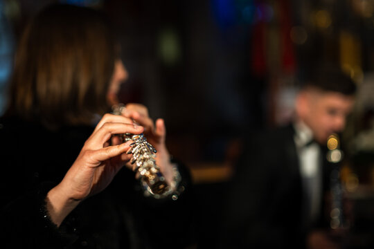 A detailed close-up shot of a female flutist's hands playing the keys of a silver transverse flute, showing intricate finger placement during a performance.