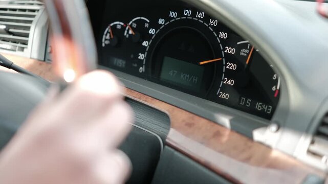 Close-up of a classic luxury car dashboard showing the speedometer and digital display while driving