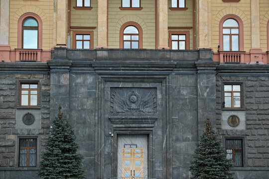 Door of the Former KGB Headquarters in Moscow with USSR Coat of Arms and Two Spruce Trees. Moody Entrance of the Former KGB Building, Moscow &ndash; USSR Coat of Arms and Evergreen Trees