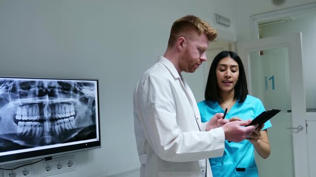 Medical team collaborating in a dental clinic while checking a patient's medical records