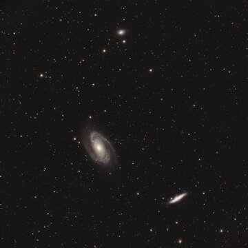 Multiple spiral and elliptical galaxies are visible against a dark night sky filled with numerous stars of varying brightness.