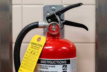 Naklejka premium Fire extinguisher on kitchen wall, close-up, pin intact, inspection tag visible, fire safety equipment concept