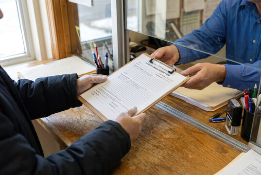 Building manager receiving damage complaint form from resident, close-up of hands and document, housing management