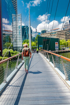 Urban waterfront scene with woman and backpack on bridge in Baltimore Maryland USA