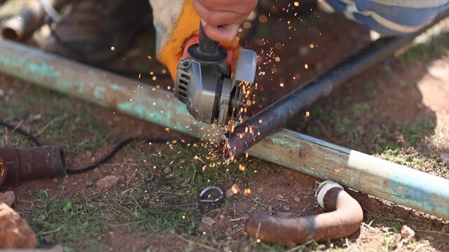 Man is cutting a metal list by angle grinder saw.