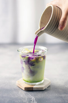 Ube tea is poured in iced matcha milk. Healthy vegan drink Ube Matcha Latte