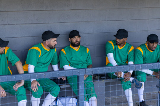 Male baseball players sitting on bench in dugout, reacting to animated stats appearing over railing