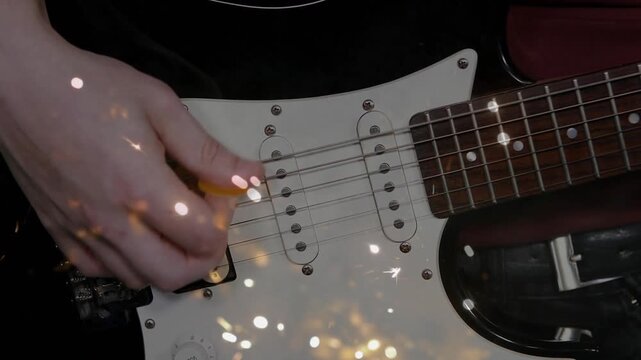 Guitarist's hand picking at bridge with pick, causing sparks peaking, fading for music over pickups