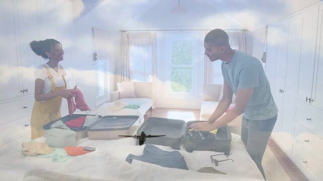 Couple packing suitcases on bed, airplane graphic appearing over couple while preparing for travel