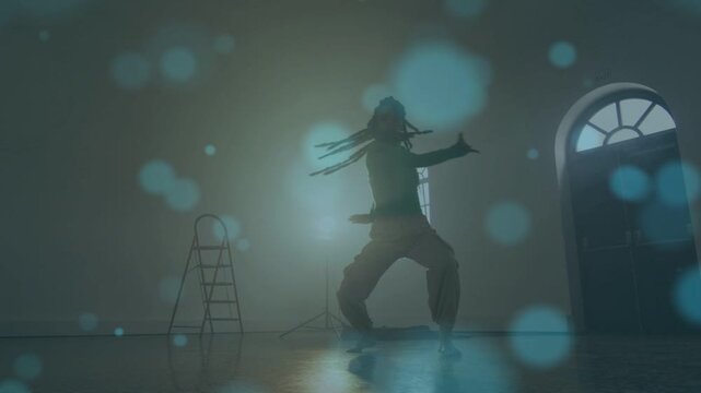 Woman dancer starting jump, rehearsing, spinning, kicking, backlit silhouette with bluish bokeh