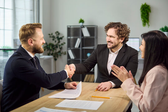 Handshake concludes interview and confirms hiring agreement. Recruiter and candidate smile in office as HR applauds, paperwork on table and positive vibe. Clear concept of hiring success.