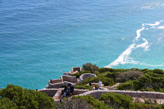 Cape Point coastal lookout scenic ocean view. High angle perspective of tourists visiting rocky cliffs and turquoise sea in South Africa ideal for travel agency promotion and holiday destination theme