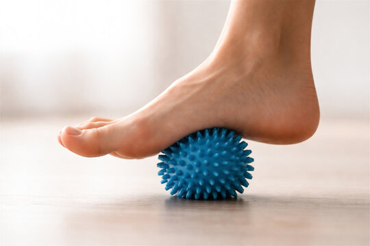 woman foot massaging with blue spiky ball. Physiotherapy exercise for plantar fasciitis relief. Self care recovery routine at home. Health and wellness therapy equipment concept