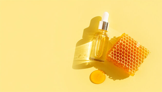 Serum bottle with honey and honeycomb arranged on yellow background. Natural organic cosmetic product for face and skin care. Moisturizing spa treatment and beauty routine concept