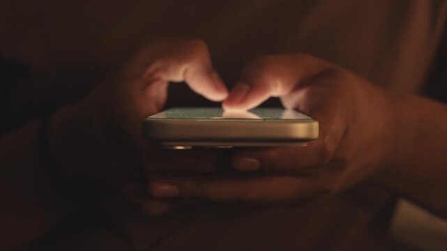 Close-up macro shot of anonymous male hands typing and chatting on a smartphone, fingers tapping a touchscreen keyboard while sending text messages in a modern digital environment. Unrecognizable pers