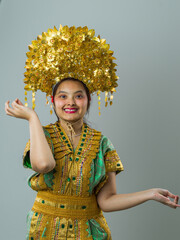 Naklejka premium Young Indonesian Asian Woman Wearing Gold Headdress and Traditional Costume Smiling in Cultural Portrait
