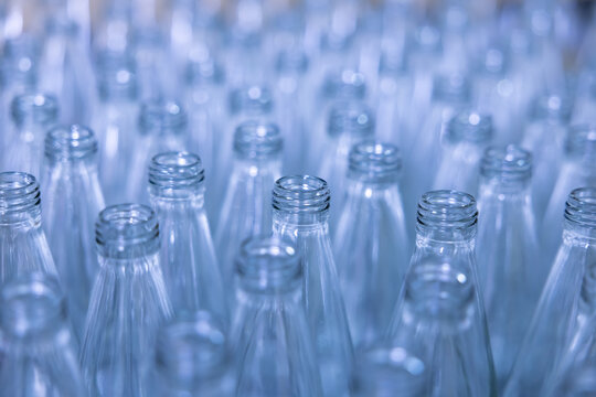 Rows of clear glass bottles placed closely together in a warehouse