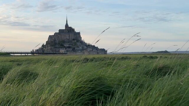 Exploring Mont Saint Michel in Normandy during the evening with green grass in the foreground and the mountain in the distance