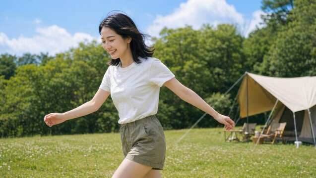 青空の下キャンプ場の芝生を笑顔で歩く女性