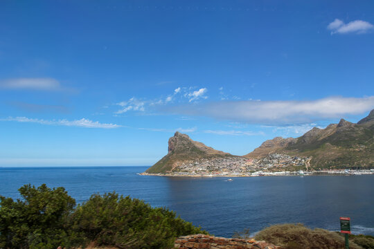 Hout Bay coastal landscape mountains Cape Town. Scenic ocean view with mountains and residential area under sunny sky South Africa ideal for travel agency brochures and nature photography themes