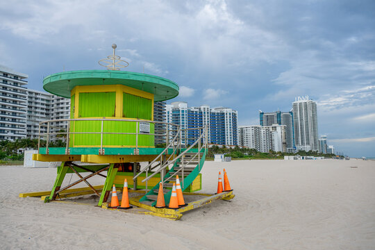 Side view of green and yellow wooden lifeguard hut. Brightly colored lifeguard post on the sand at 57th Street Miami Beach under overcast sky.