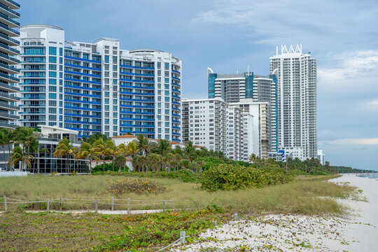 Modern high rise residential buildings along the Miami Beach coast. Modern blue and white apartment towers with palm trees and sand dunes on the Atlantic coast in Miami Beach, Florida.