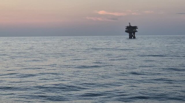 An offshore wellhead platform with sunset background