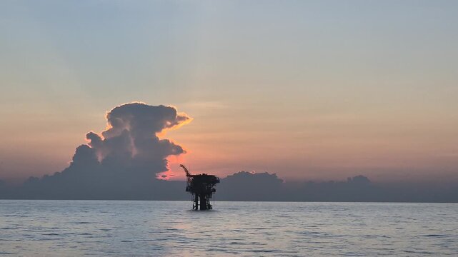 An offshore wellhead platform with sunset background