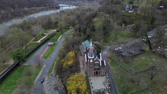 Lower Town Harpers Ferry frames Shenandoah Street beside river rail line near confluence. Warm roof tones, early-spring trees, soft hillside shadows shape textures in WV