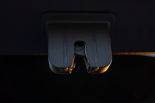 Close-up of trunk latch striker on a modern car body, showing the metal locking catch for the rear hatch inside the luggage opening.