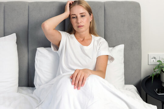 Woman feeling headache sitting in bed at home