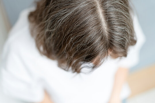 Close up of a woman peacefully accepting her graying hair with soft gentle smile. The mature adult has made peace with natural aging signs completely. Mother embraces her silver strands with love.