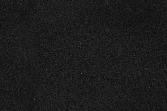 Dark film grain black paper seamless texture background. Old dust and scratch grunge effect overlay.
