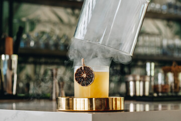 Smoky, garnished cocktail. A bartender prepares a cocktail with smoke effect and dried fruit garnish at a lively bar during the evening. © Анна Терелюк