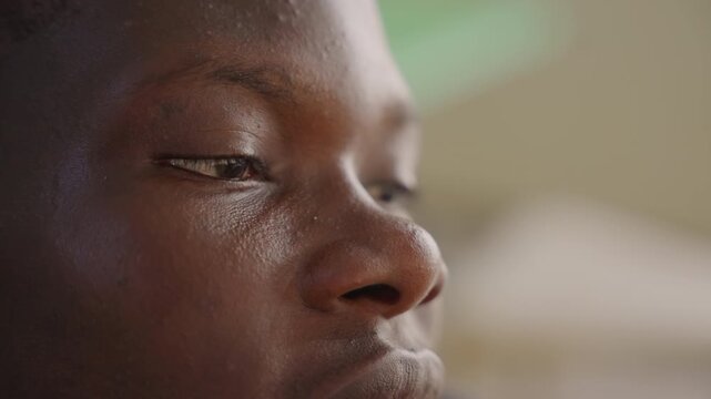Black man gentle gaze close portrait, quiet romantic anticipation while reading message, student rehearsing vows in thought, poet composing line with half smile, shopkeeper remembering first kiss,