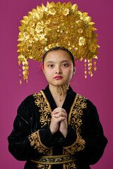 Naklejka premium Young Indonesian Asian Woman Wearing Ornate Gold Headdress And Embroidered Black Traditional Costume Portrait