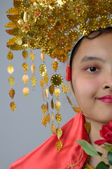 Naklejka premium Portrait Of Young Indonesian Asian Woman Wearing Ornate Gold Traditional Headdress And Red Costume For Celebration