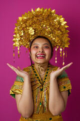Naklejka premium Young Indonesian Asian Woman in Golden Traditional Headdress and Embellished Costume Celebrating Cultural Festival