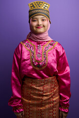 Naklejka premium Young Indonesian Asian Girl in Traditional Malay Costume and Hijab Posing Against Purple Background