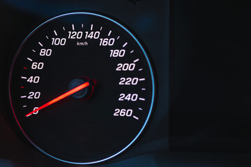 Fototapeta premium Illuminated car dashboard speedometer at night. Close up view of vehicle speed gauge in the dark.