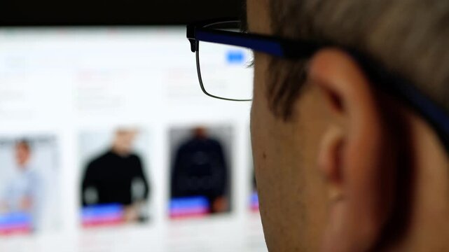 Man browsing online clothing store. He selects outfits on website with various fashion styles. Shopping experience captures modern consumer behavior and trends in fashion.