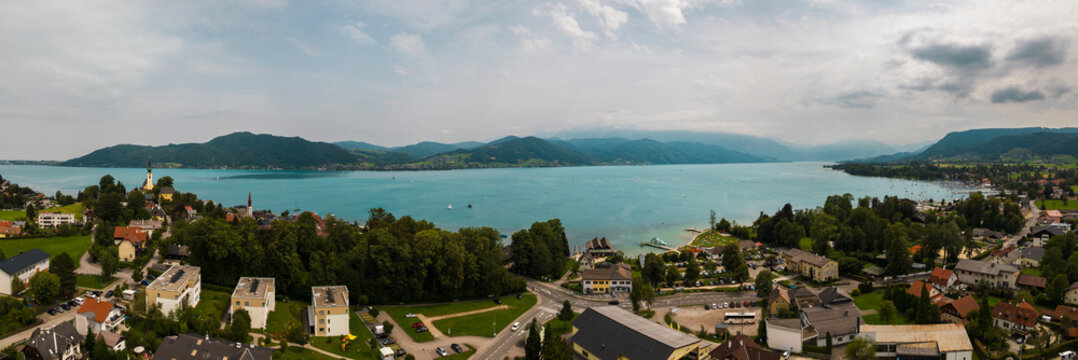 Panoramic aerial view of Attersee am Attersee with lake, mountains, and church on a bright summer day in Austria.
