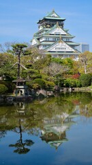 Naklejka premium Osaka Castle reflected in pond with traditional Japanese garden