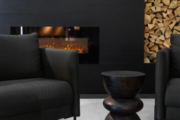 Obraz premium Living room interior with fireplace and logs. Modern furniture and decorative side table.