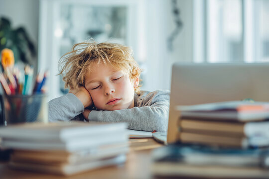 Tired child sleeping at desk with school supplies