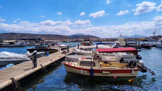 Photo of small leisure boats and traditional fishing vessels moored at Varkiza harbor on the Athens Riviera, a scenic seaside suburb of greater Athens.