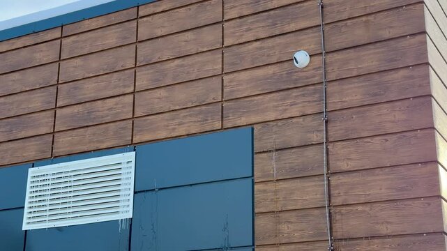 Snow covered storage unit with iron door. Security camera mounted above entrance monitors quiet winter yard, brick and metal