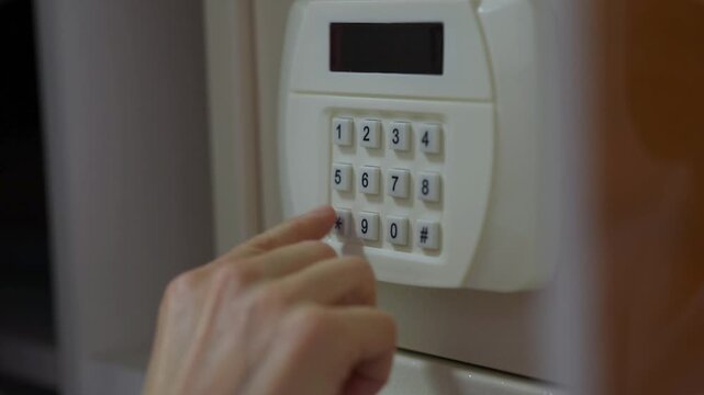 Female hand is typing a secret password combination on a digital safe to open it for valuables