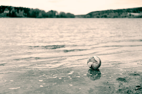 Abandoned Soccer Ball on the Shore of a Nordic River in Muted Tones